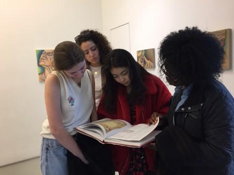 Scholars peruse a catalogue at the Judy Chicago exhibit PowerPlay