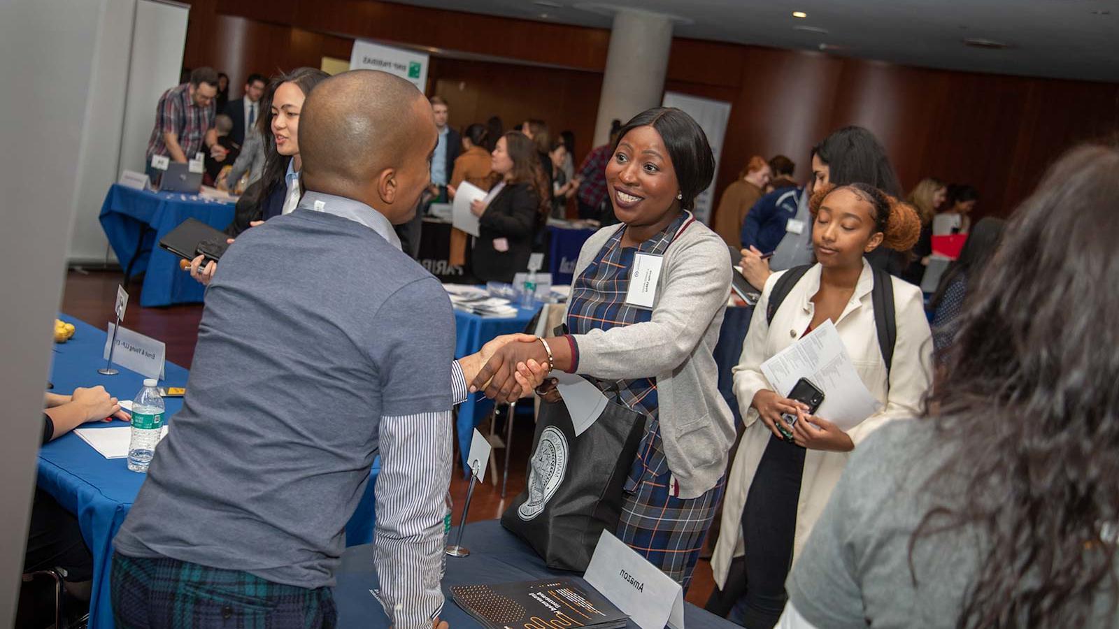 Black woman shakes hands with an employer at a busy networking event