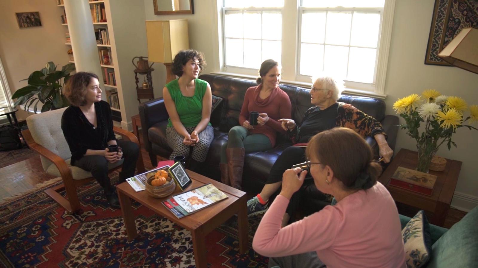 Several women of different ages seated in a living room