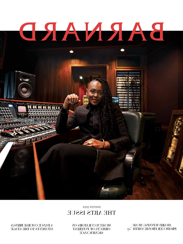 Music producer Ebonie Smith looks at camera seated next to a recording control board