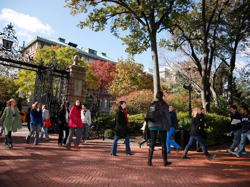 Students walking on campus near entrance gates in the fall
