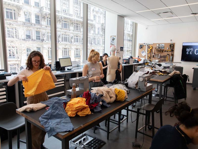 Students work with fabric in a large room with sewing machines