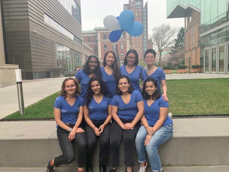 8 students posed outside, wearing matching blue shirts