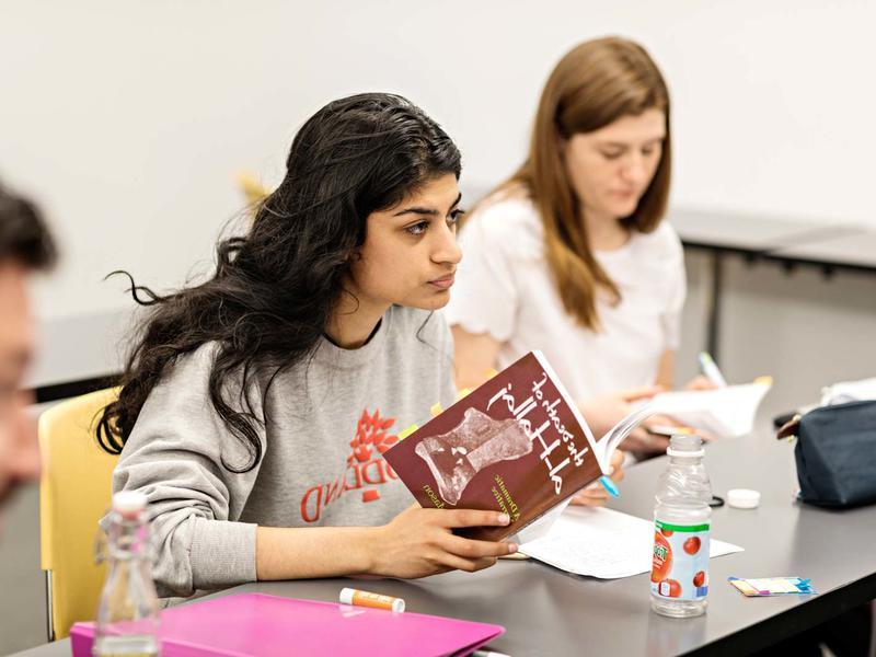 Student in a literature class, holding a text