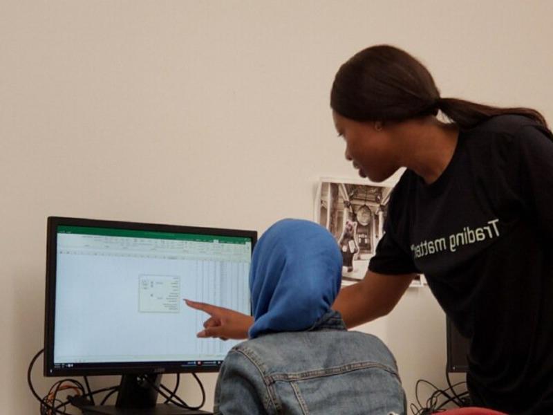 A student points at a computer screen to show another student