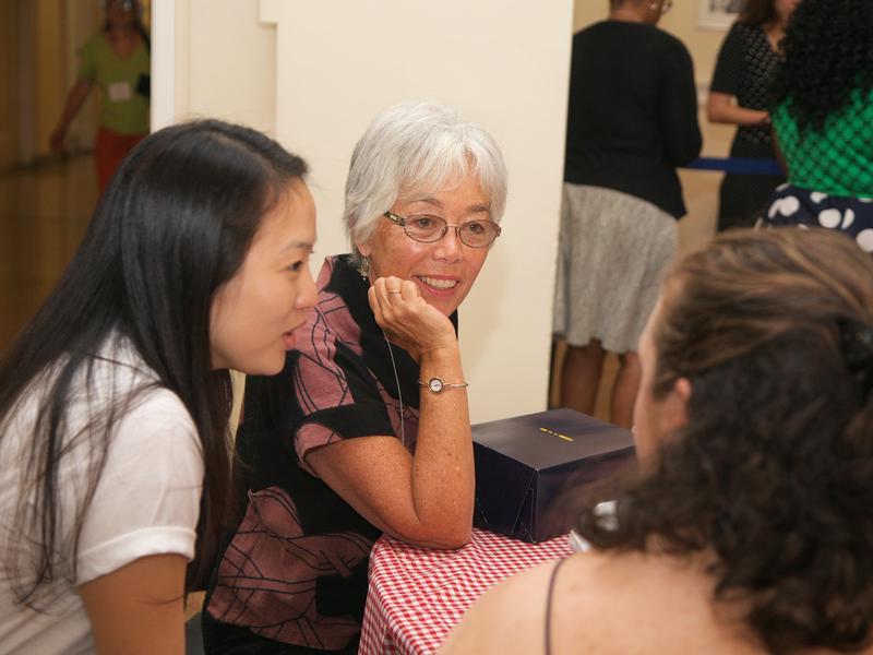 An older alum listens attentively to 2 younger women